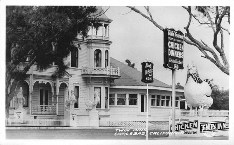 Historic building with 'Twin Inns' sign and large chicken statue in Carlsbad, California.