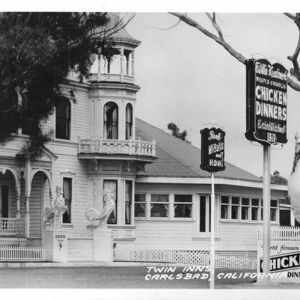 Historic building with 'Twin Inns' sign and large chicken statue in Carlsbad, California.