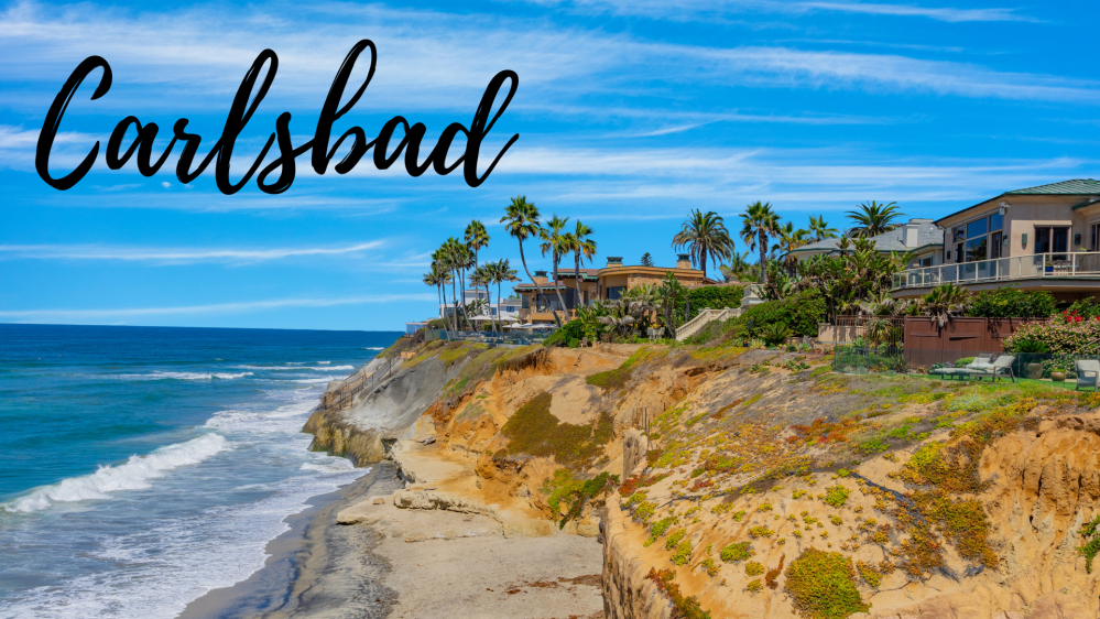 Coastal view with cliffs, ocean, palm trees, and houses; text 'Carlsbad' at top left.