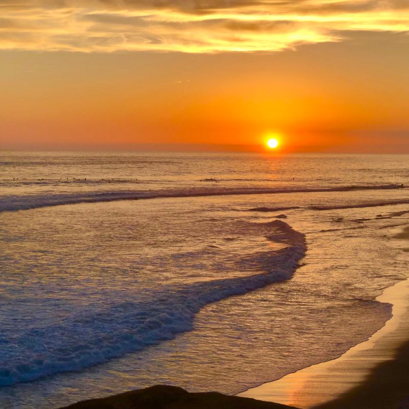 a sunset over a beach next to the ocean