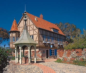 Historic medieval-style building with red roof and a small pavilion in front.
