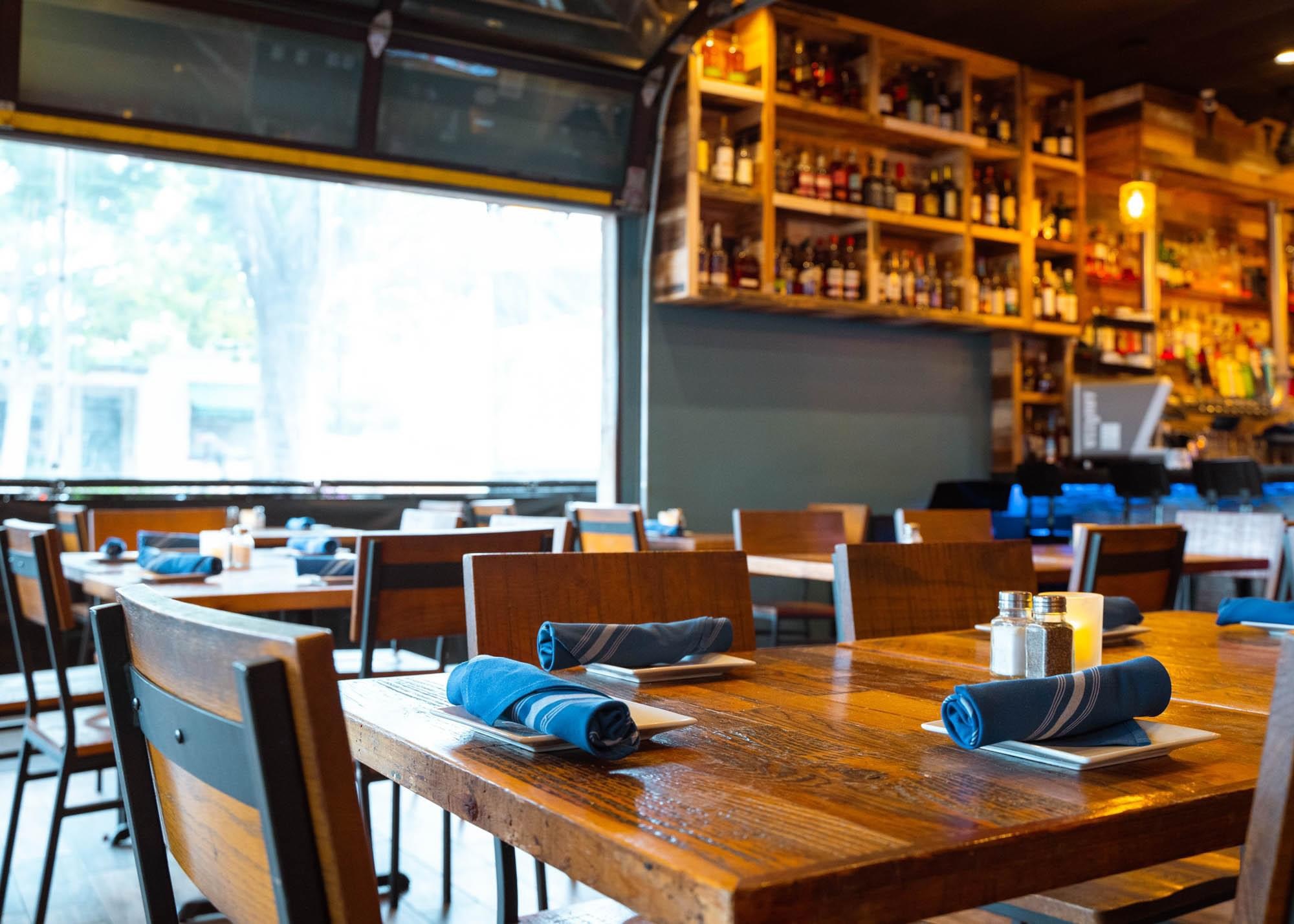 Cozy restaurant interior with wooden tables and blue napkins.