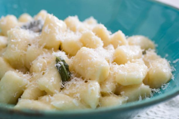 a bowl filled with pasta and broccoli on a plate