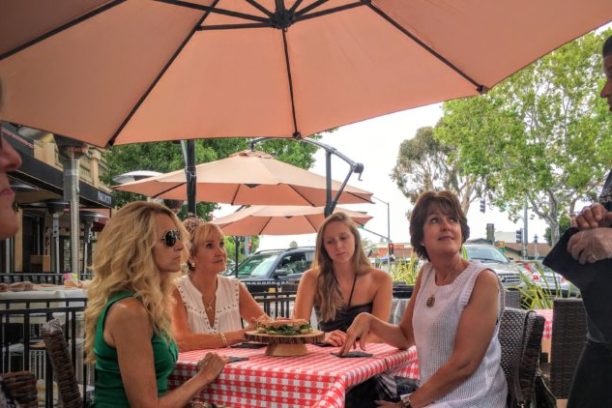 a group of people sitting at a table with an umbrella