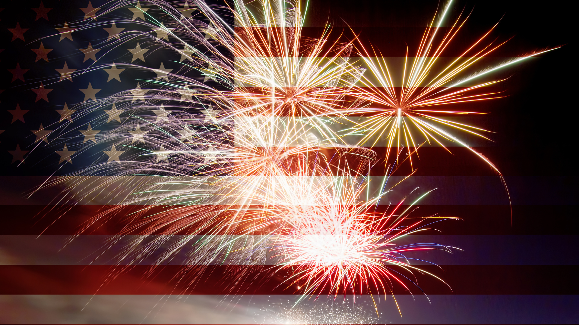 Fireworks in front of a faded American flag at night.