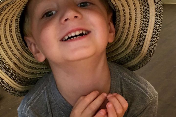 a little boy wearing a hat and smiling at the camera