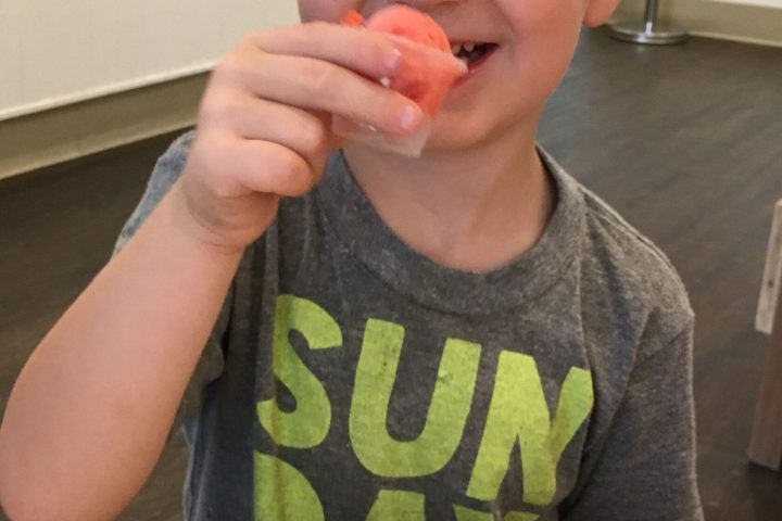 a little boy sitting at a table eating food