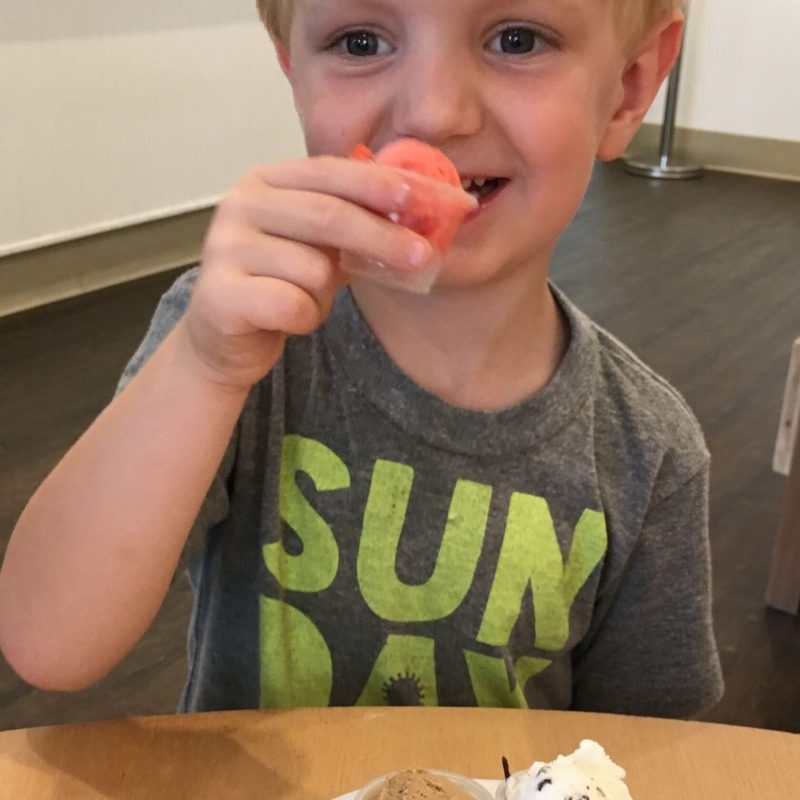 a little boy sitting at a table eating food