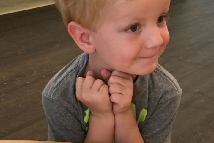 a little boy sitting at a table eating food