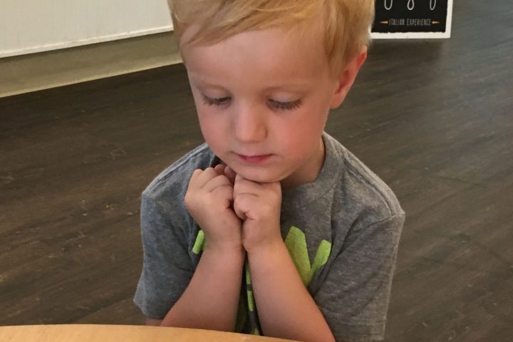 a little girl sitting at a table eating food