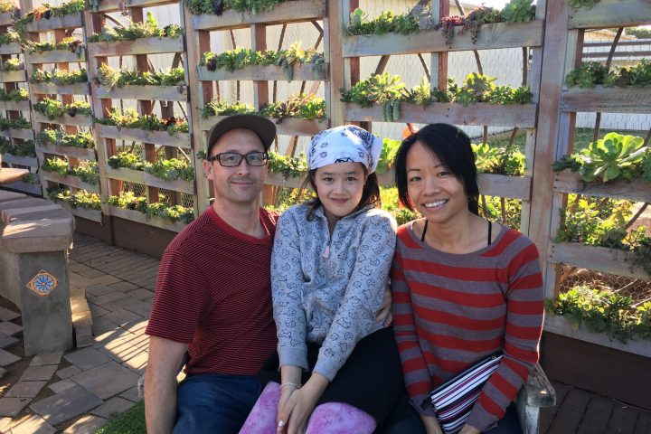 a man and a woman sitting on a bench posing for the camera