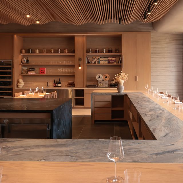 Modern kitchen with marble countertops, wood ceiling, and open shelves.