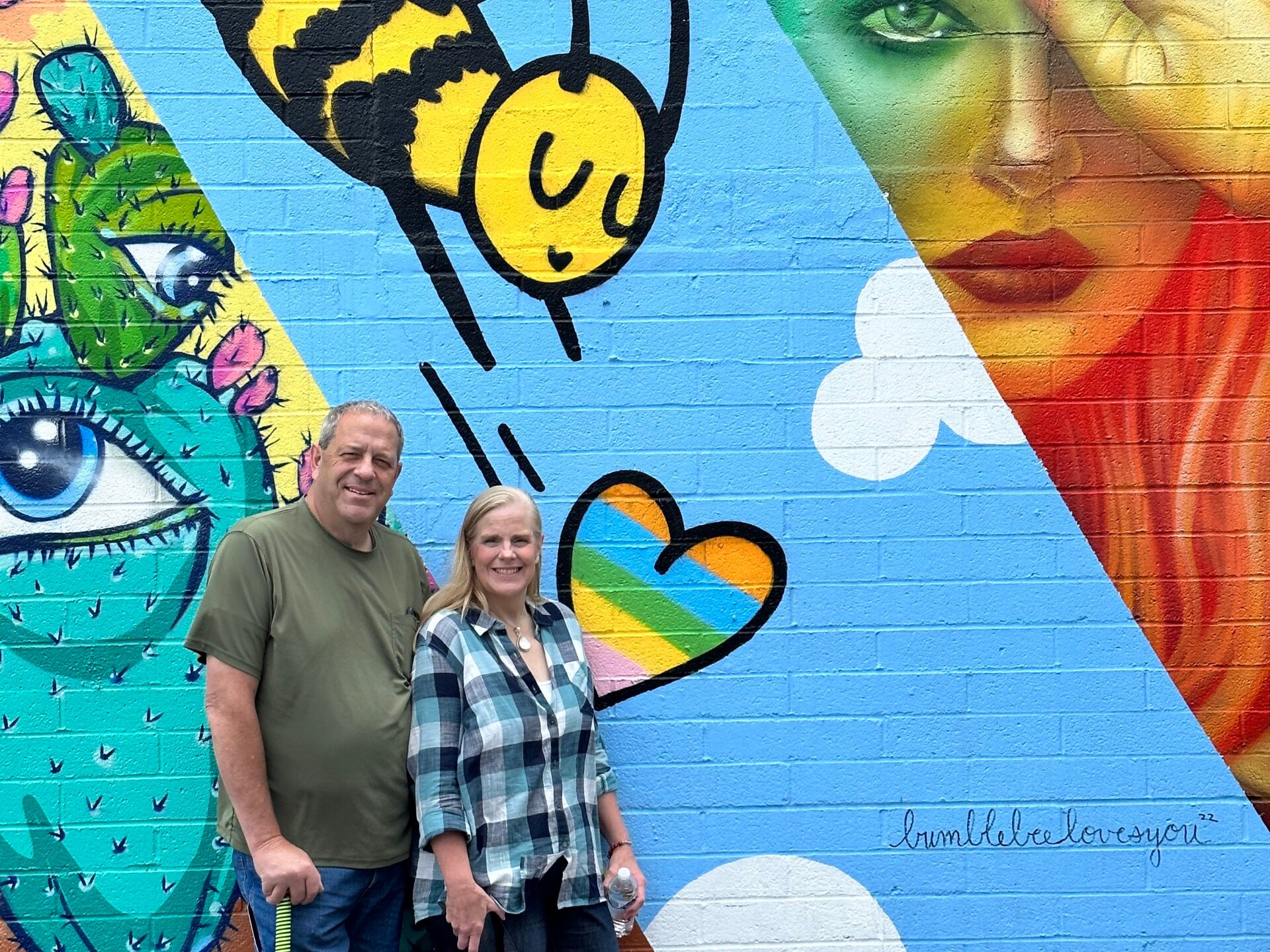 a group of people standing next to a graffiti covered wall