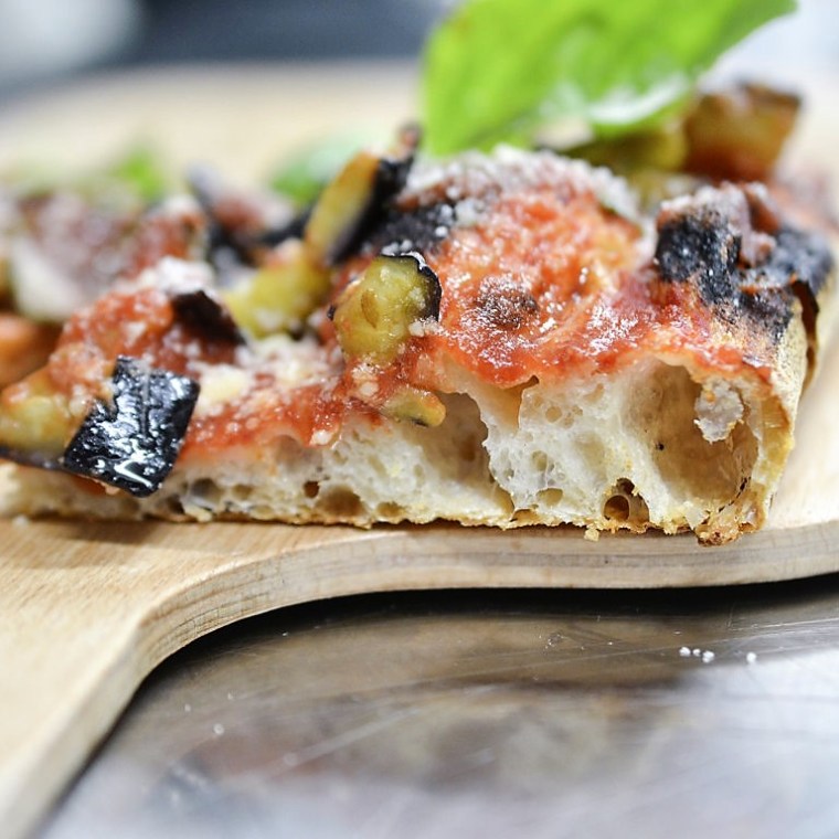 a slice of pizza sitting on top of a wooden cutting board