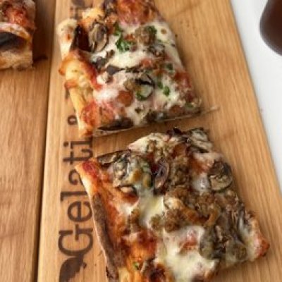 a slice of pizza sitting on top of a wooden cutting board