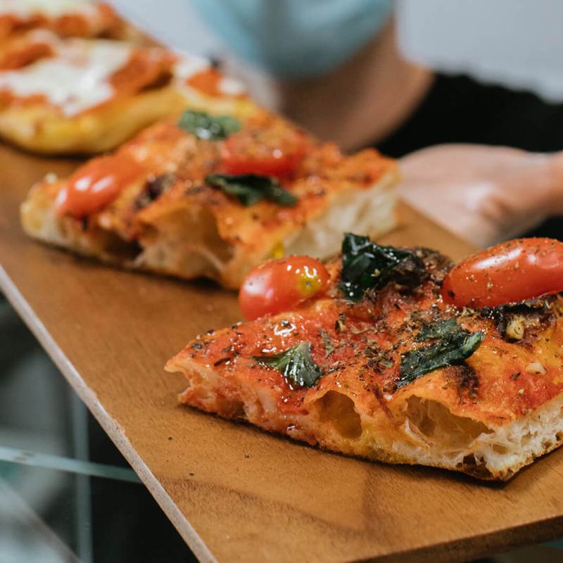 a slice of pizza sitting on top of a wooden cutting board