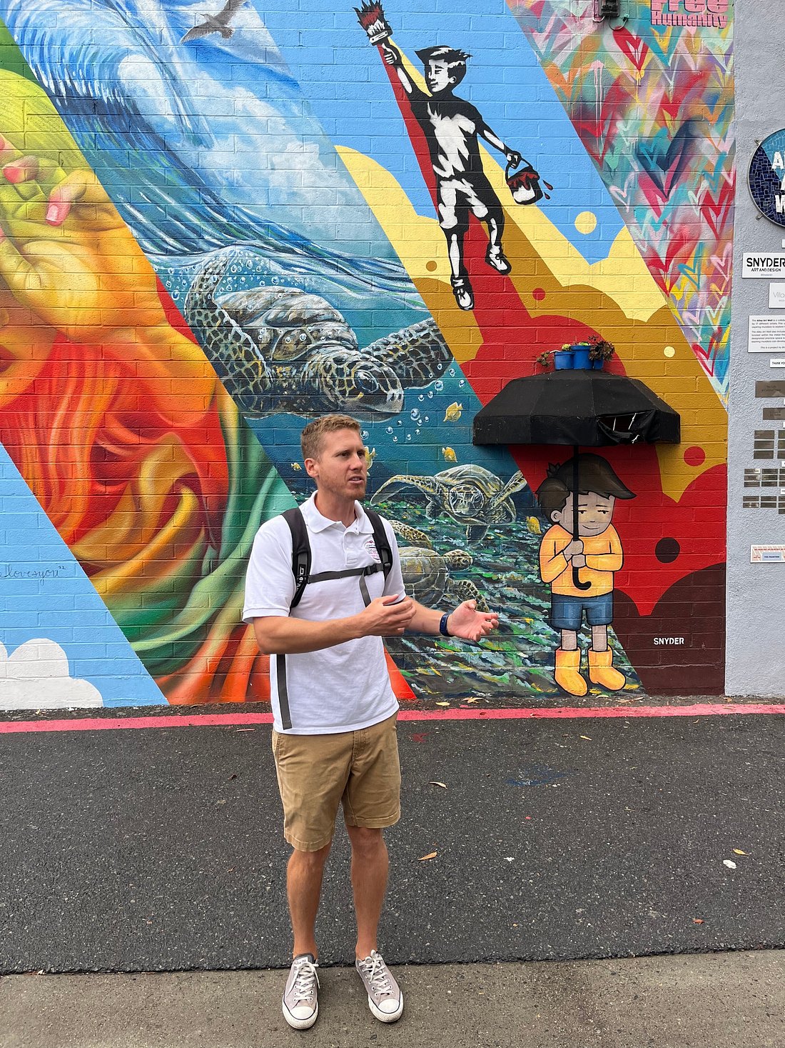 a man holding a kite while standing on a sidewalk