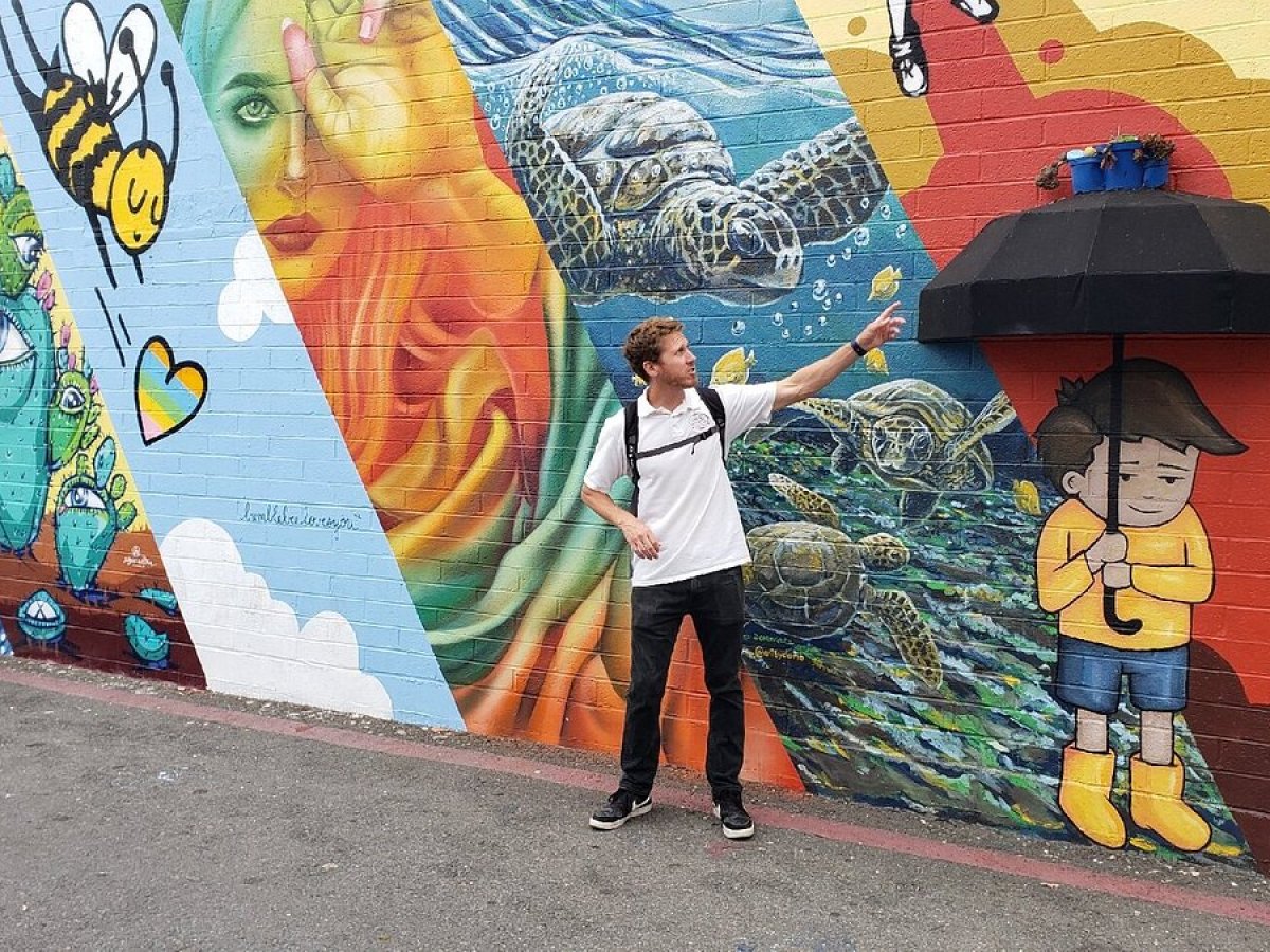 a man and a woman standing next to a graffiti covered wall