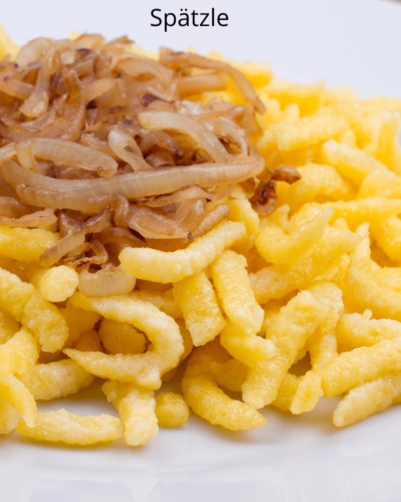 Close-up of spätzle with caramelized onions on a white plate.