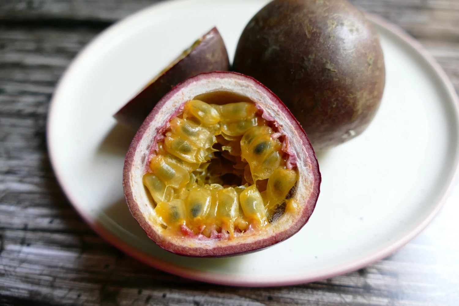 Halved passion fruit with seeds on a plate.