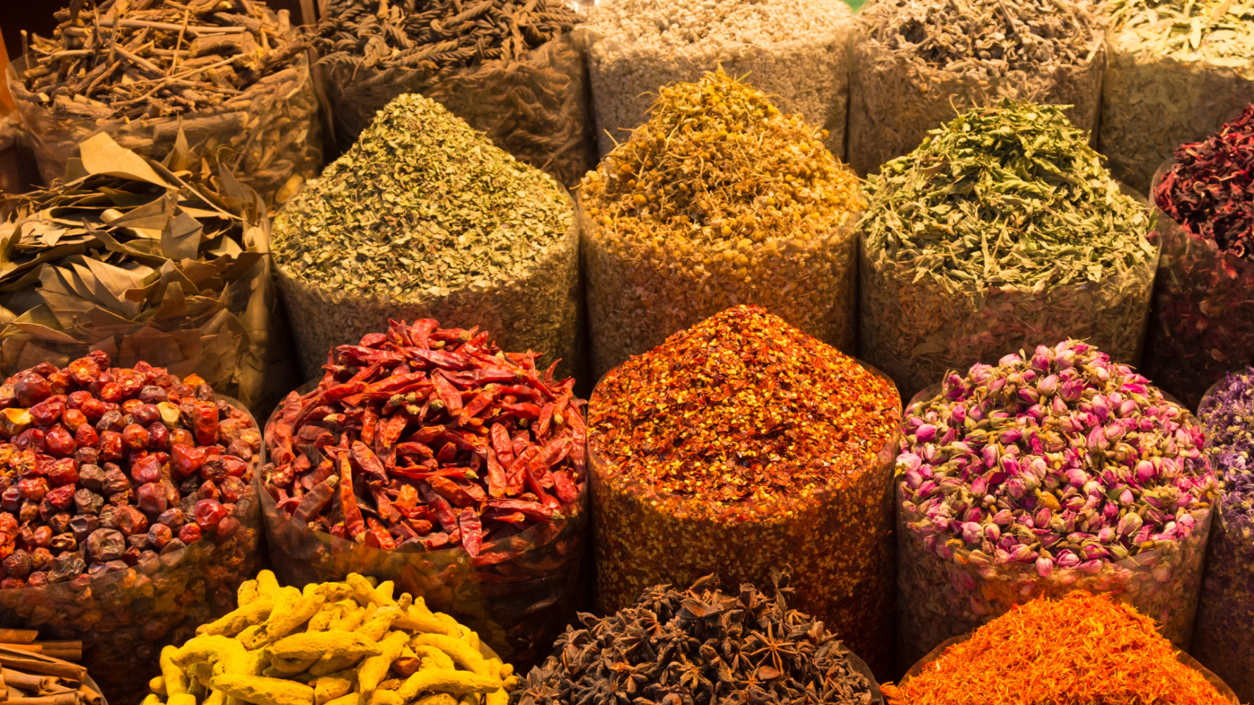 Colorful spices and herbs in bags at a market display.