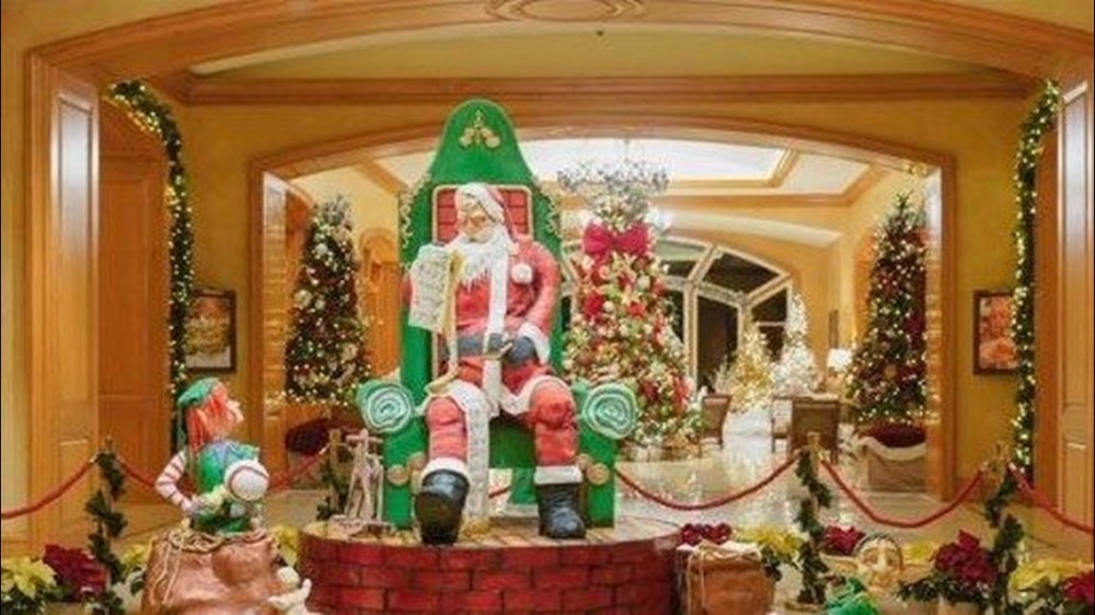 Festive room with Santa and elf sculptures, Christmas trees, and holiday decorations.