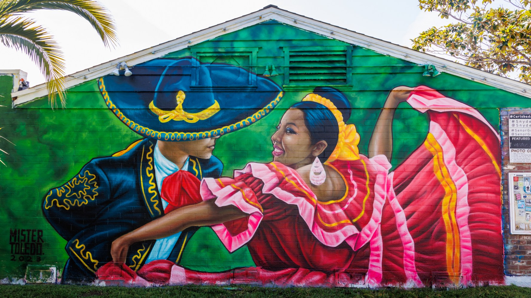 Colorful mural of two dancers in traditional attire on a building wall.