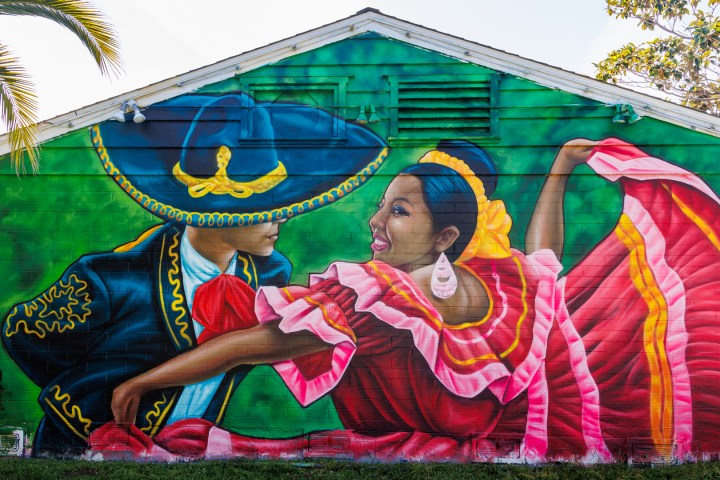 Colorful mural of two dancers in traditional attire on a building wall.