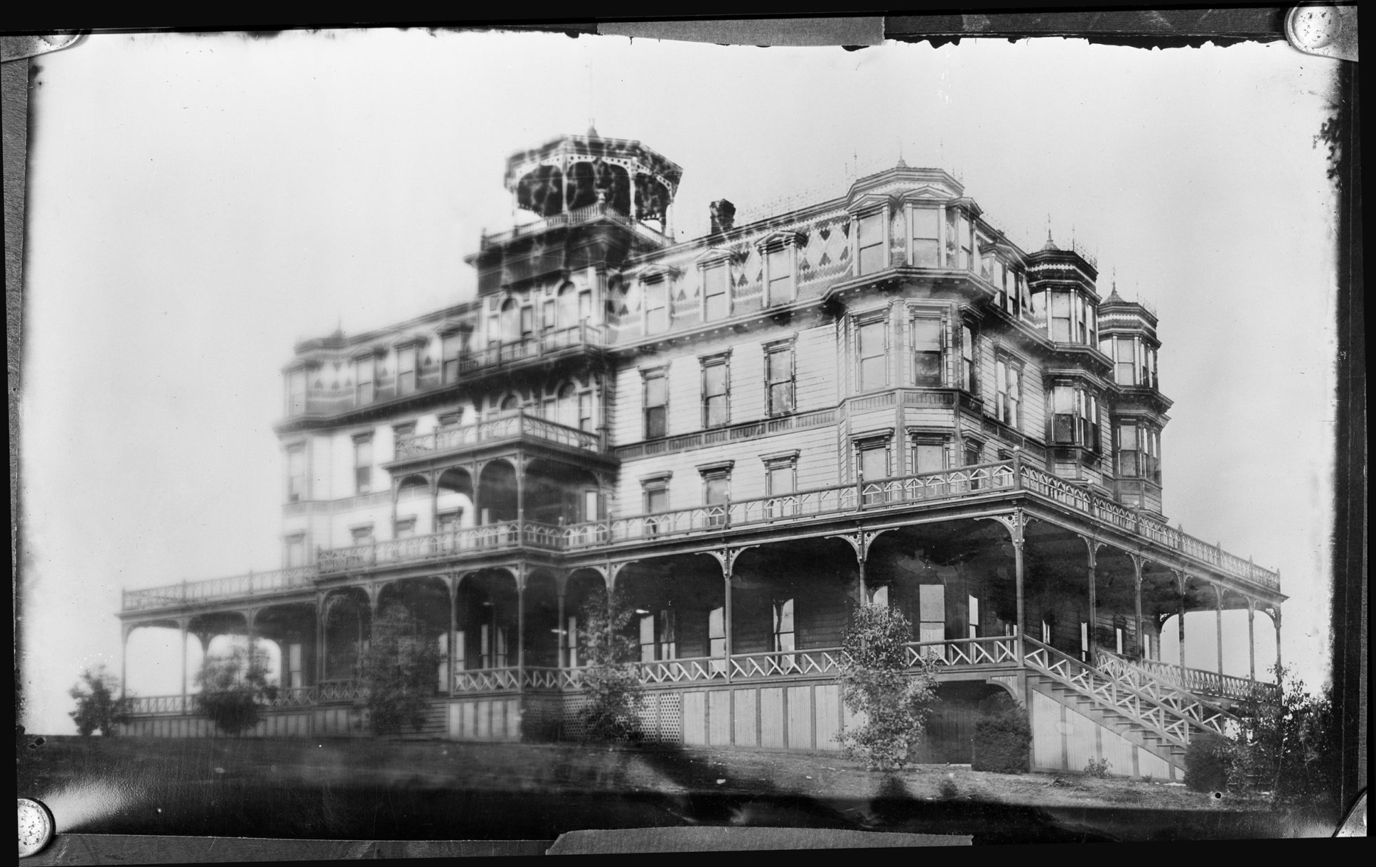Vintage photo of a large Victorian-style mansion with wraparound balconies.