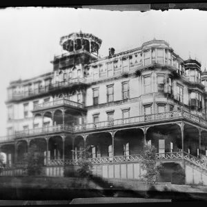 Vintage photo of a large Victorian-style mansion with wraparound balconies.