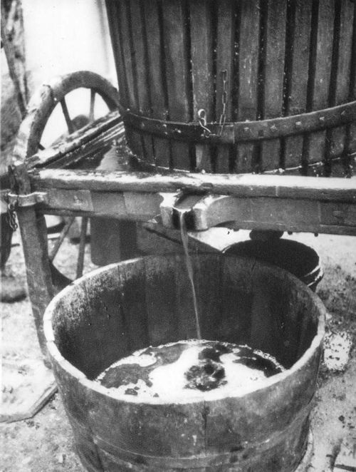 Historic grape press with juice flowing into a wooden barrel.
