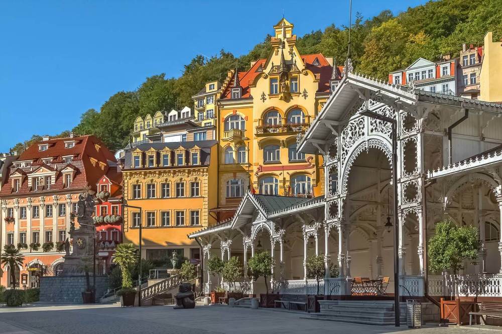 Colorful historic buildings and ornate white pavilion in a sunny town square.