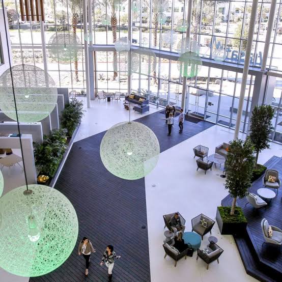 Spacious modern lobby with large spherical lights, seating areas, and people walking.