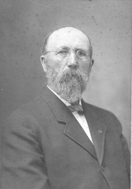 Vintage portrait of a bearded man in a suit with glasses.