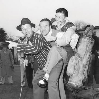 Three men playing around with golf equipment, one on another's back, outdoors.