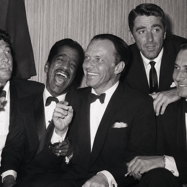 Five men in suits, smiling and laughing together in a vintage black and white photo.
