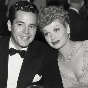 Black and white photo of a man in a tuxedo and a woman in a dress, smiling and seated closely.