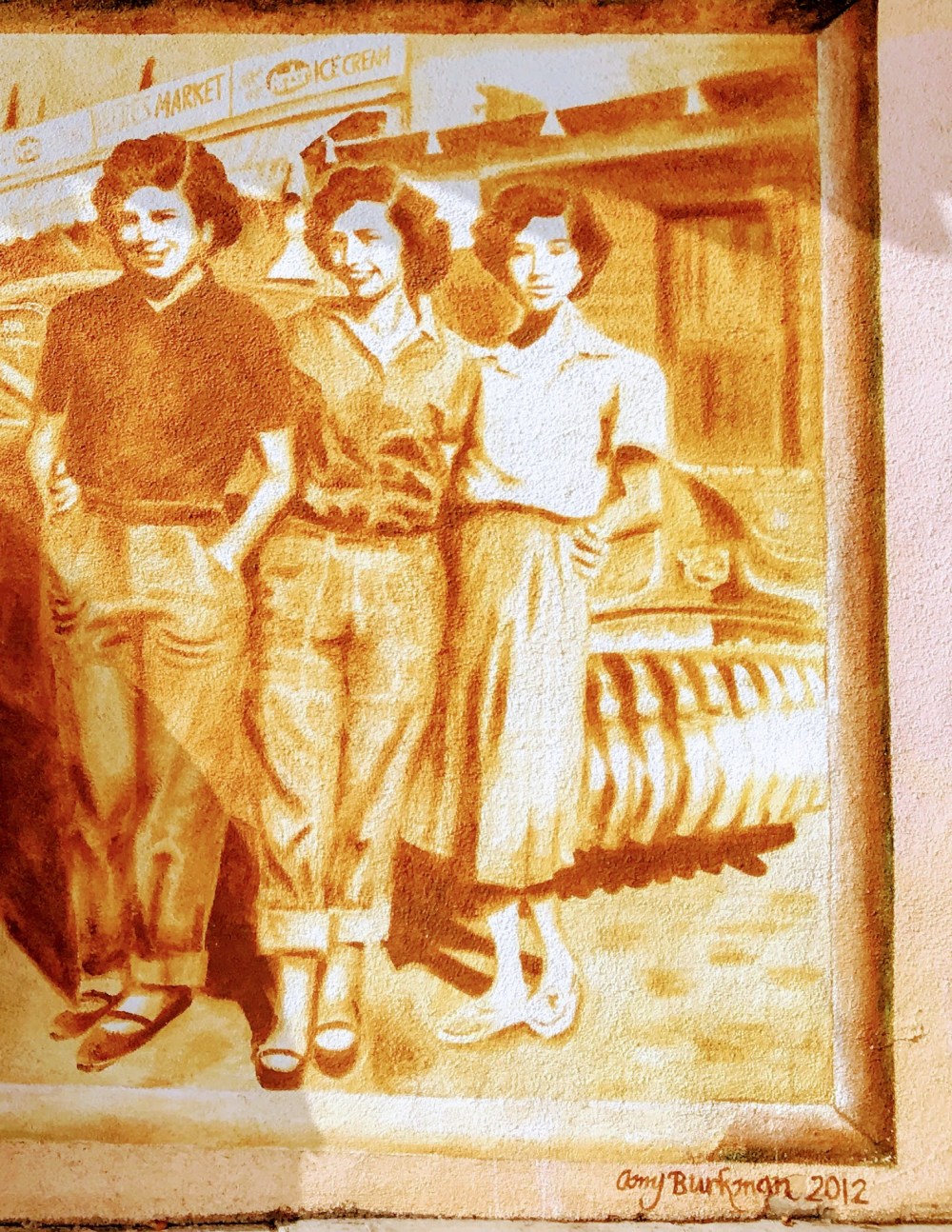 Sepia mural of three people standing in front of a car, smiling, 1950s style.