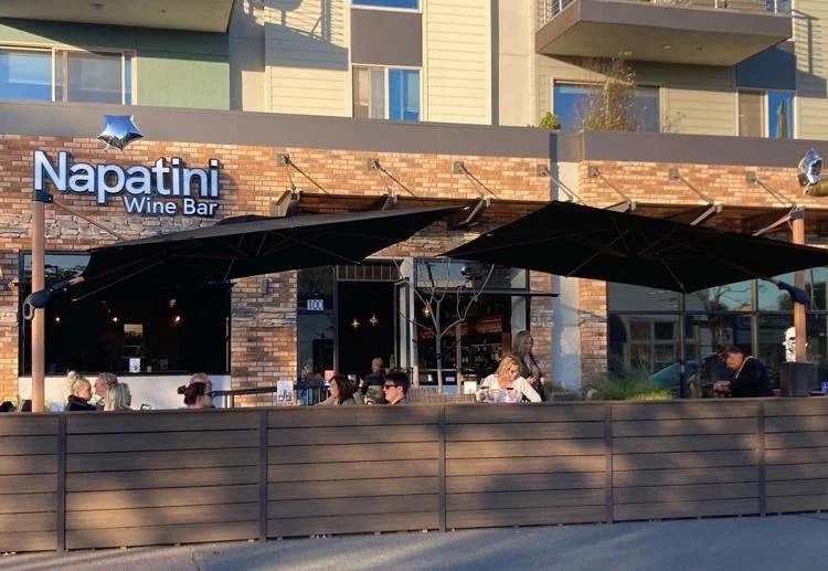 Outdoor seating at Napatini Wine Bar with customers on a sunny day.