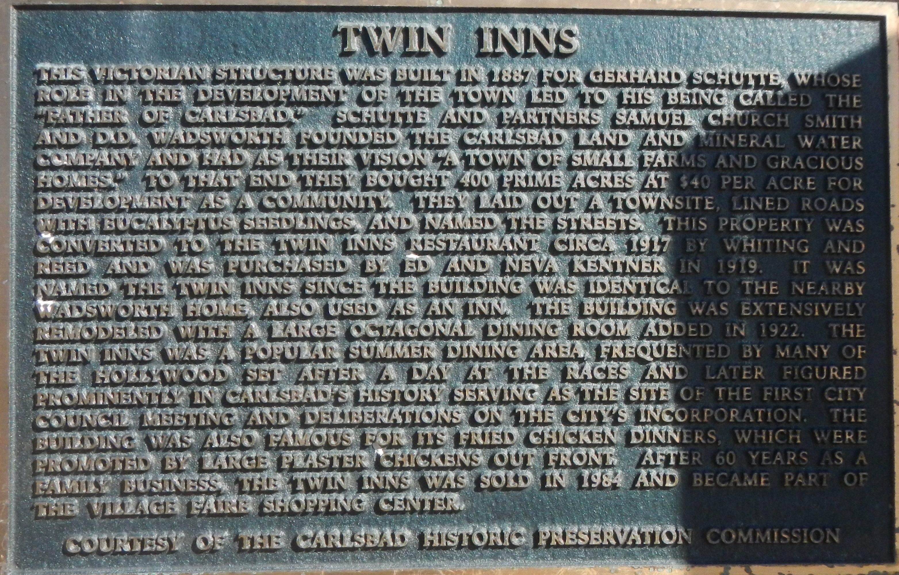 Plaque on brick wall detailing the history of Twin Inns.