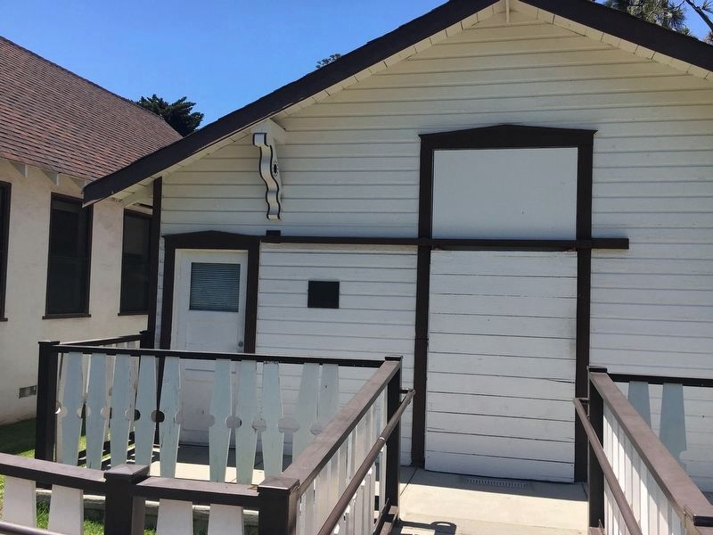 White wooden building with brown trim and a ramp leading to the door.