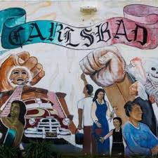 Colorful mural with people, fists, and 'Carlsbad' banner.