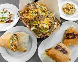 Assorted Mexican dishes including tacos, fries with toppings, and a sandwich.