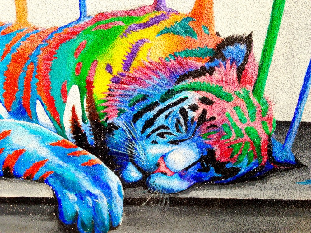 Colorful tiger mural with vibrant stripes, lying down on a surface.