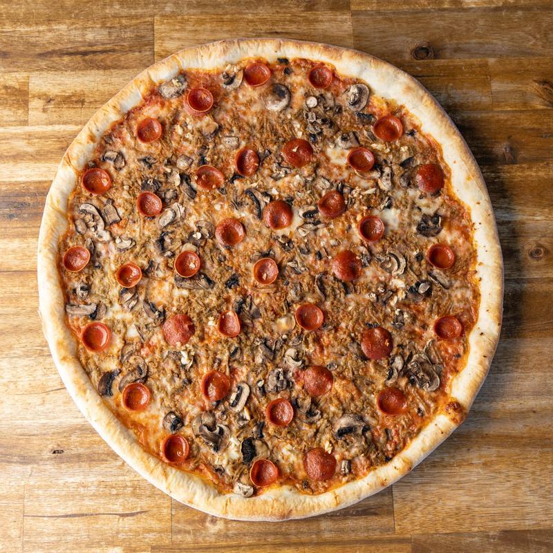 Pizza with pepperoni, mushrooms, and sausage on a wooden surface.