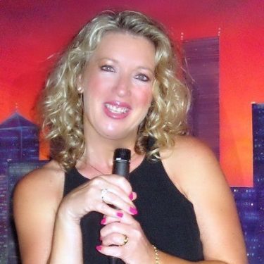 Smiling woman holding microphone, cityscape backdrop.